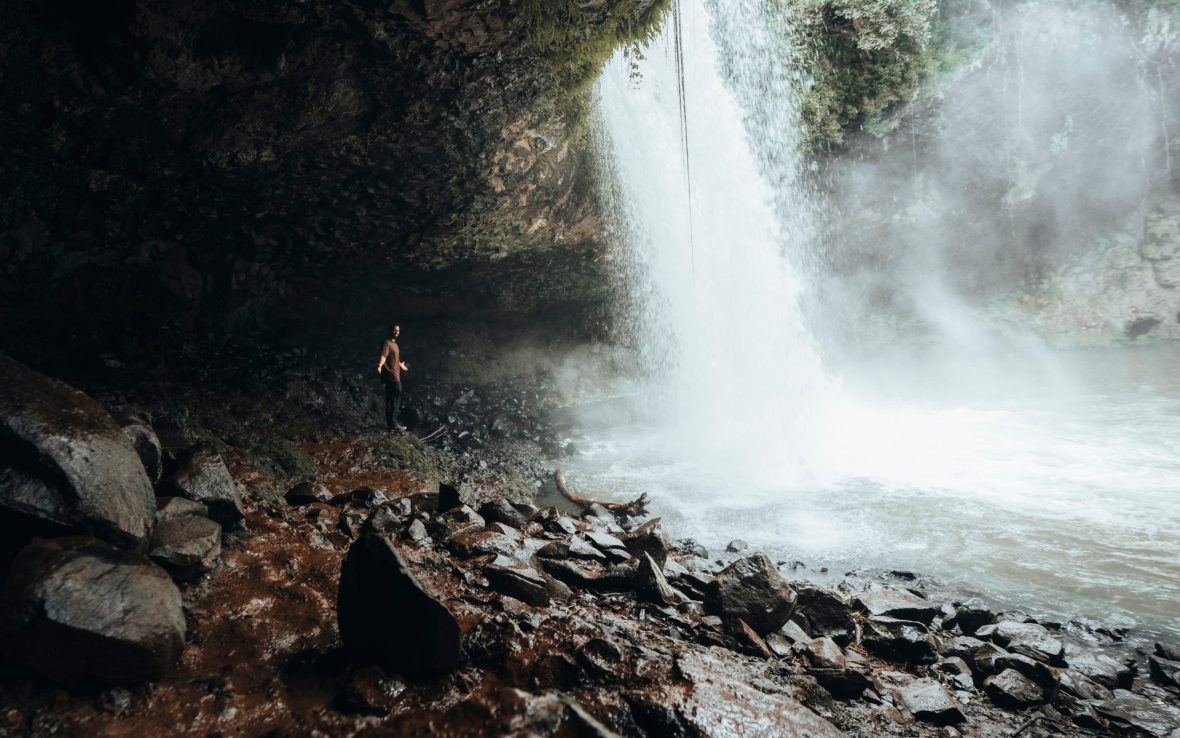 Man stands next to gushing waterfall