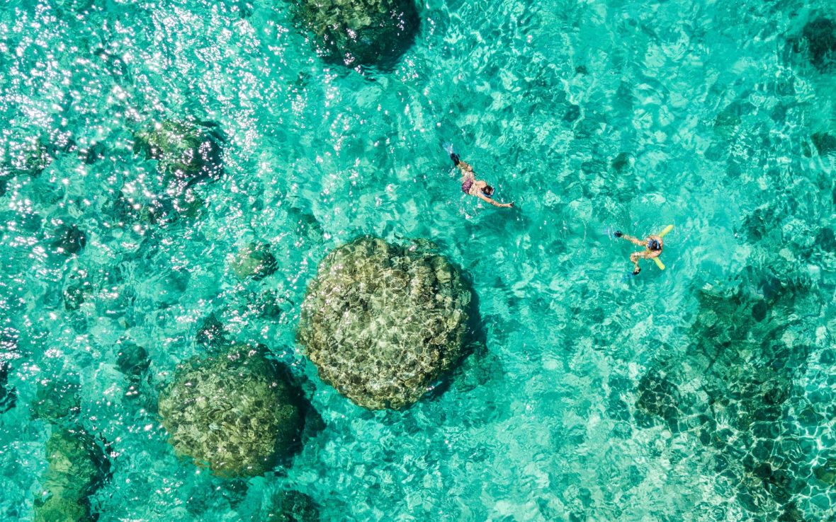 A birds eye view of man snorkeling in turqoise water