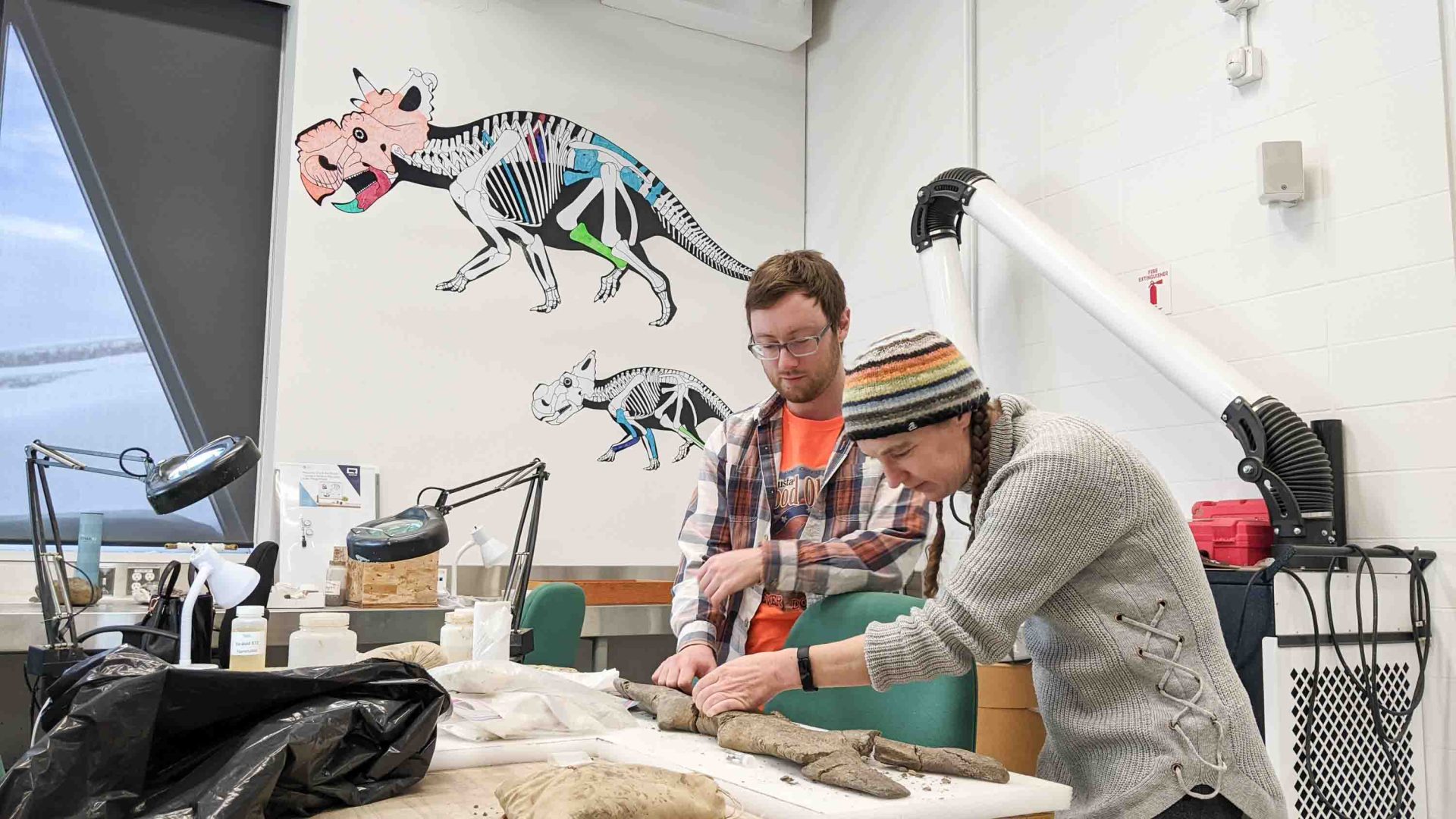 Two people work on a fossil in a lab.