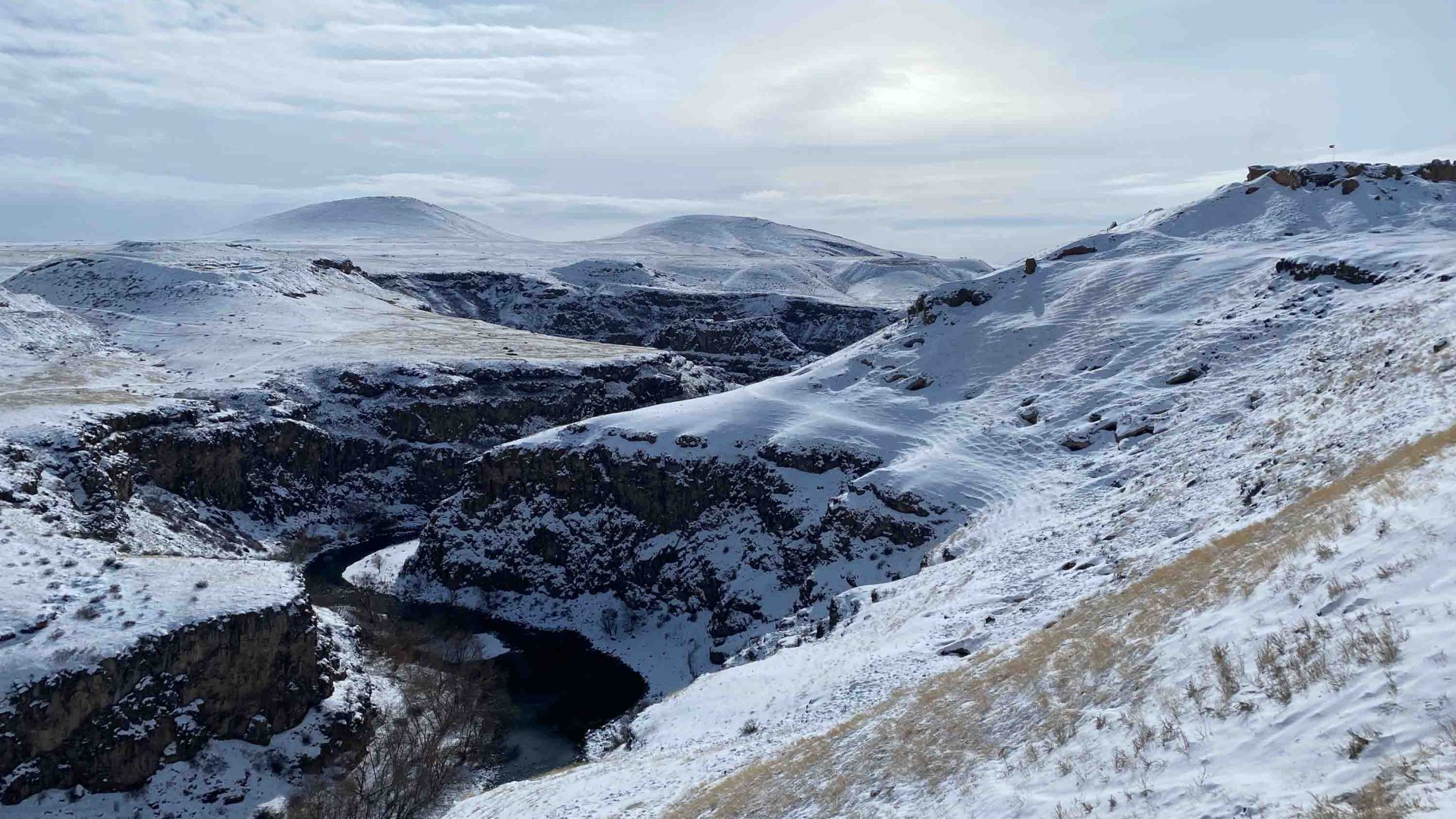 A river winds below snowy mountains.