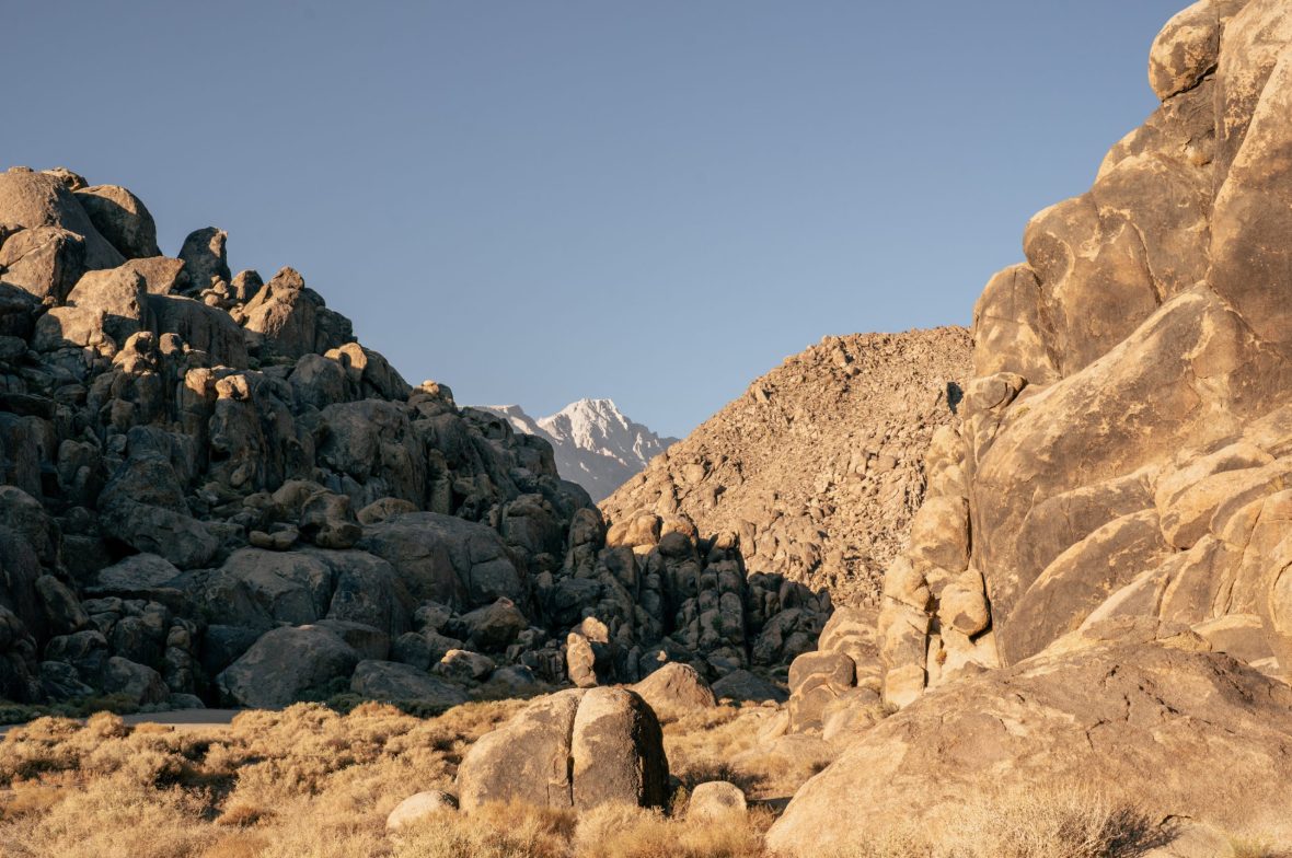 View of snow-capped Sierra Nevada mountain range between boulders