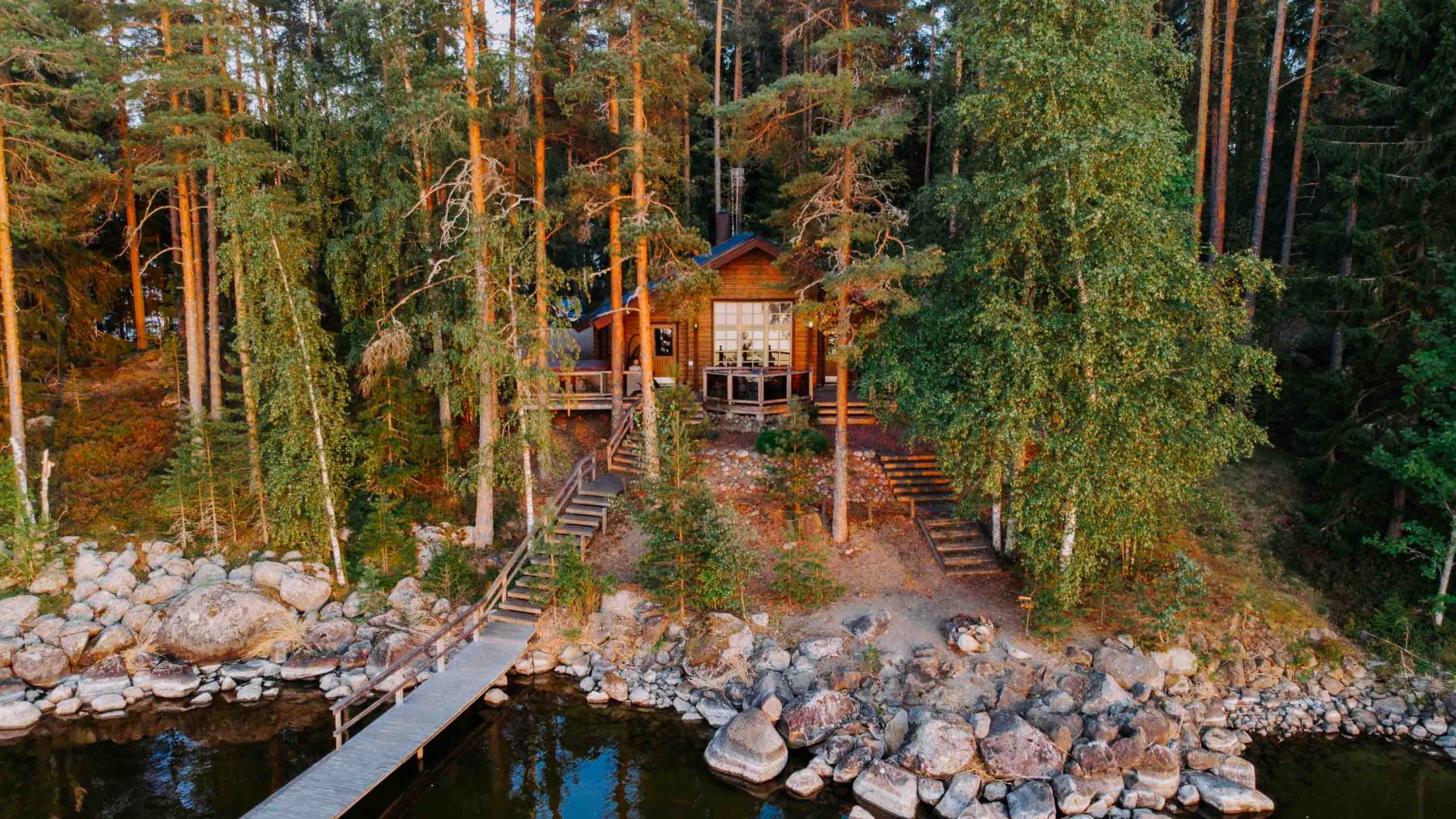 A house in a forest setting that is overlooking a lake.