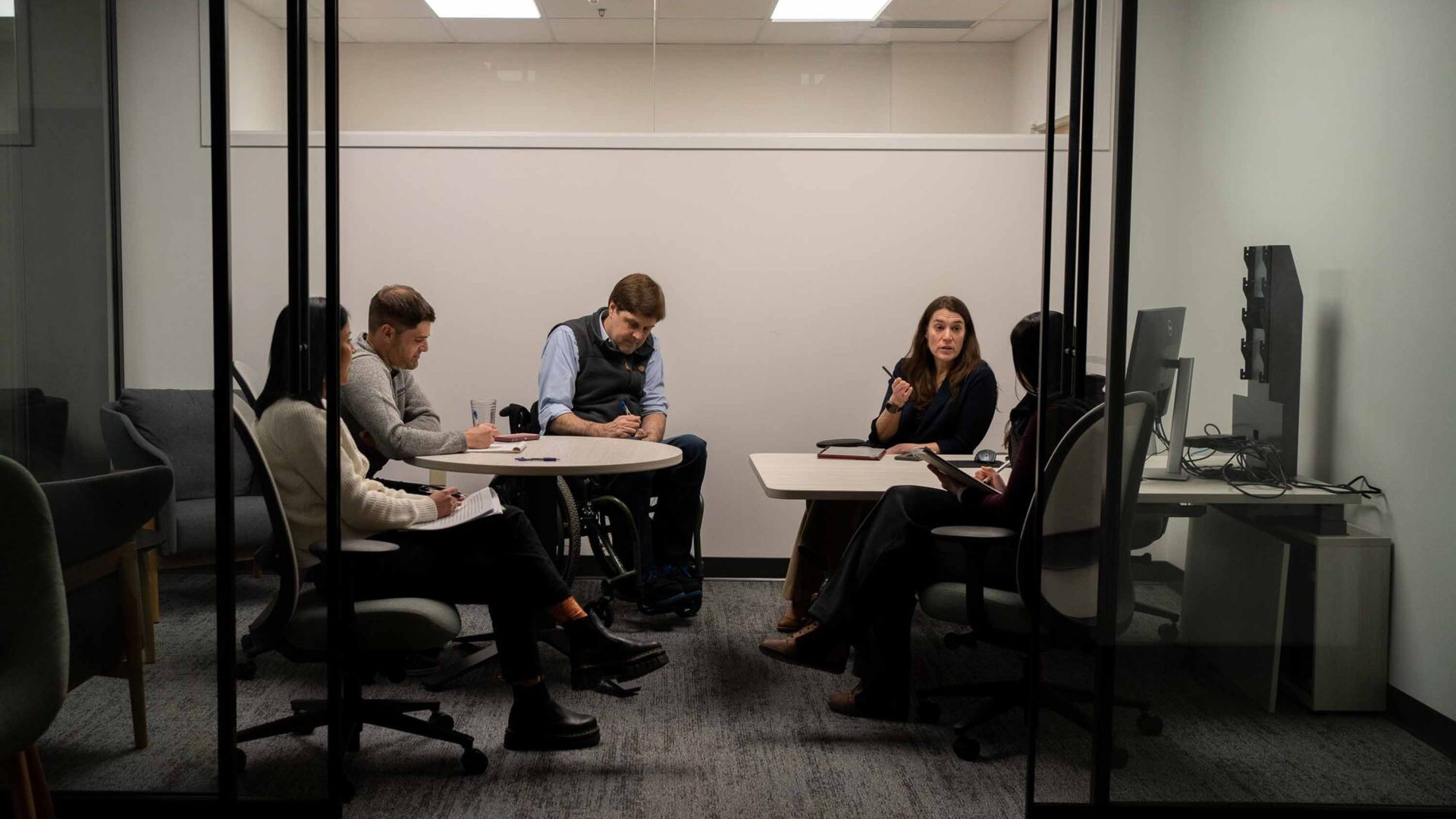People sit around a table during a meeting and write on papers.