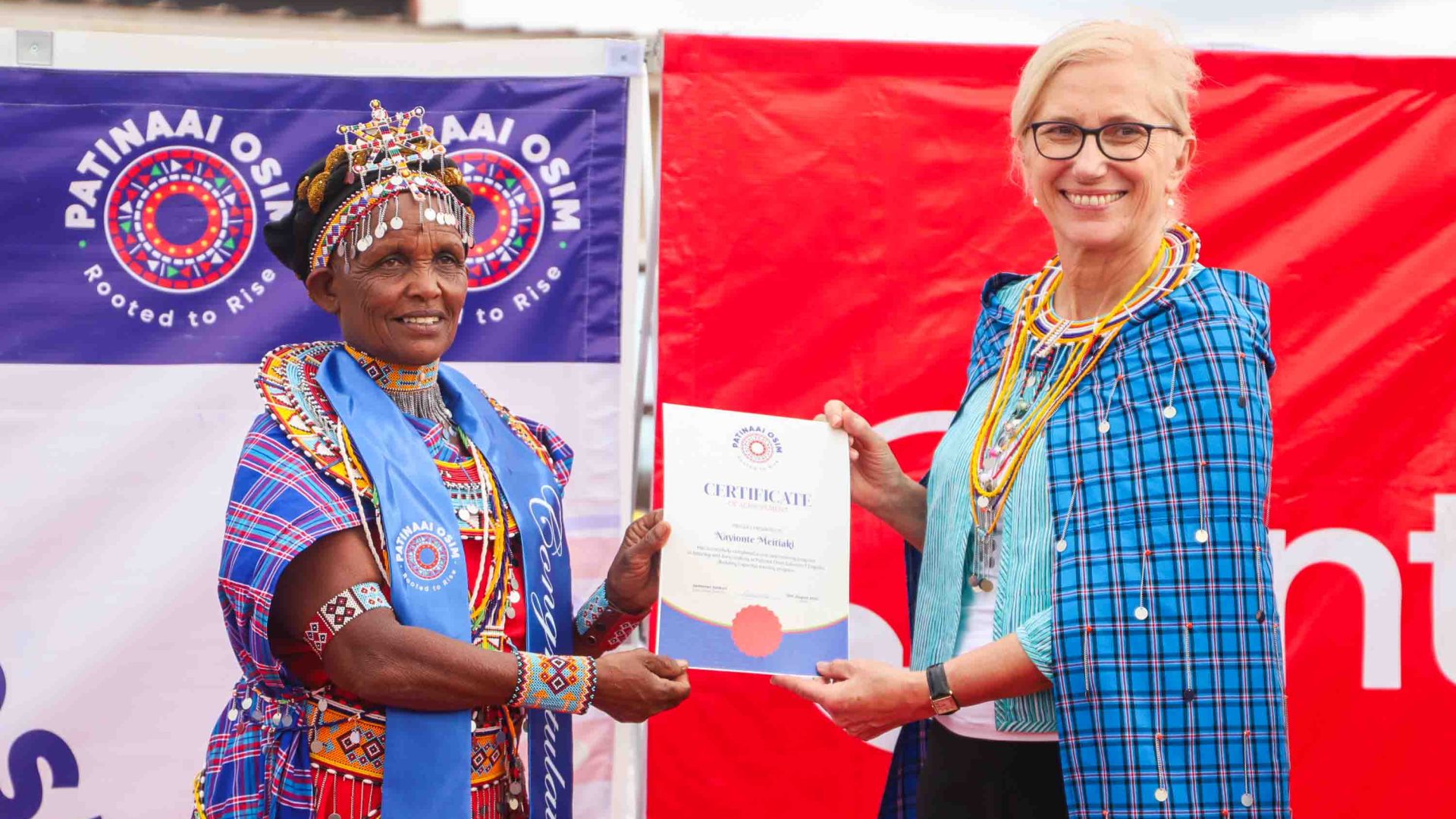 A Maasai woman receives a certificate from another woman.