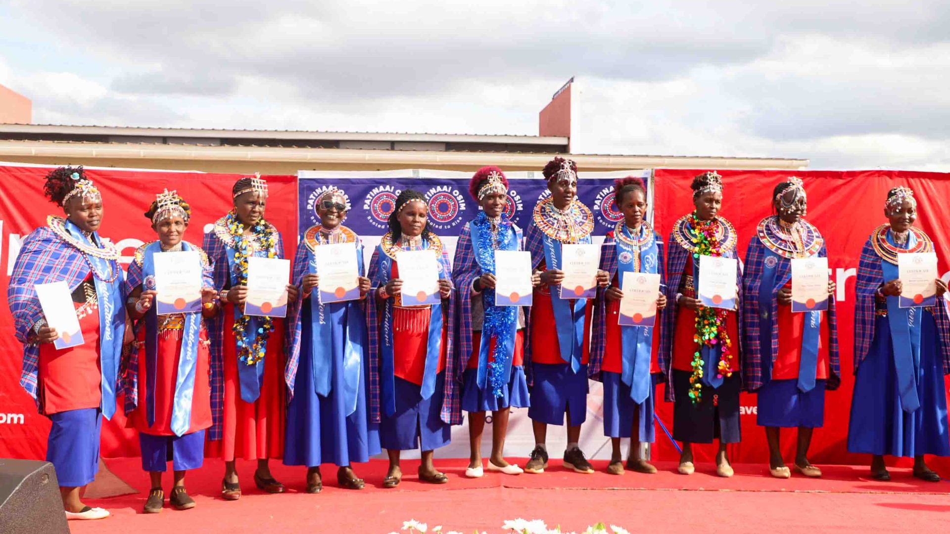 Women stand on stage holding their certificates.