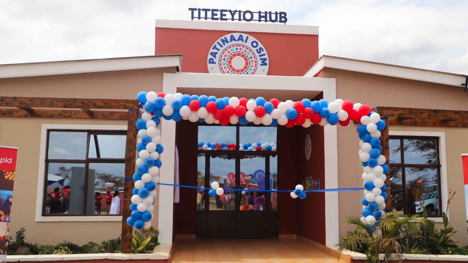 The exterior of a building with celebratory red, white and blue balloons in an arch around the entry.