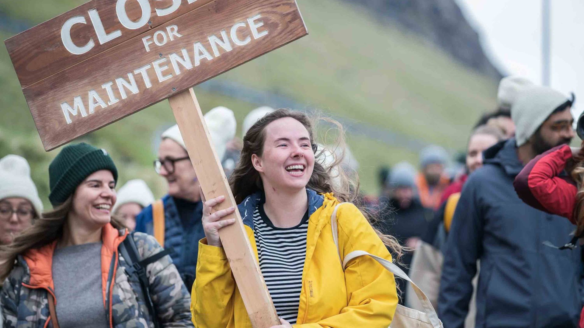 A group of people smile as they hold a sign that says "Closed for maintenance".