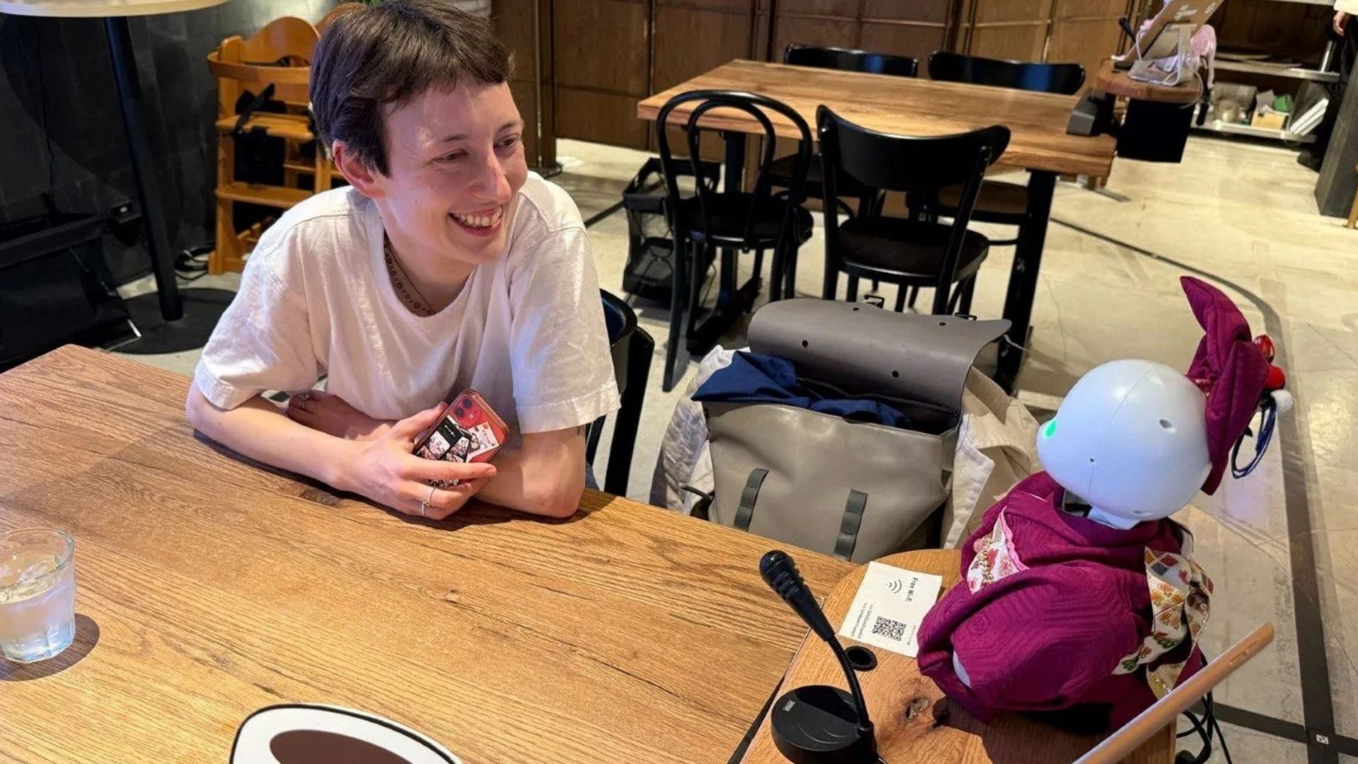 A customer in a cafe smiles and laughs with a robot server